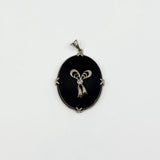 Vintage 14ct white gold black onyx pendant with diamond bow centre on white background.