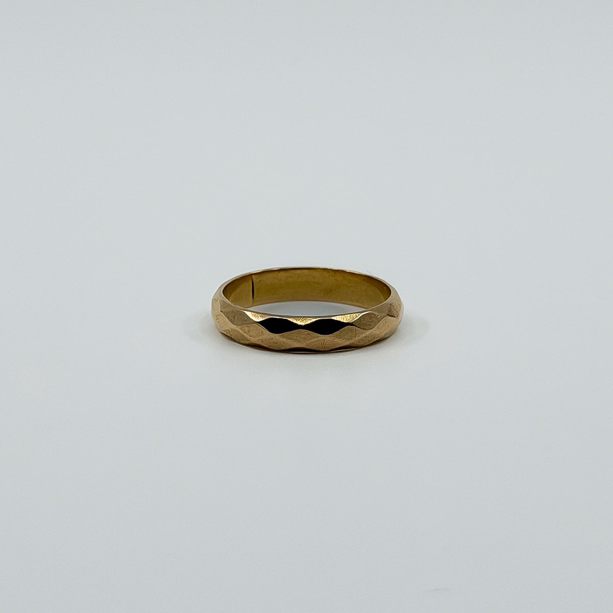 Vintage 18ct rose gold faceted band ring laid flat, showing the polished full band design.