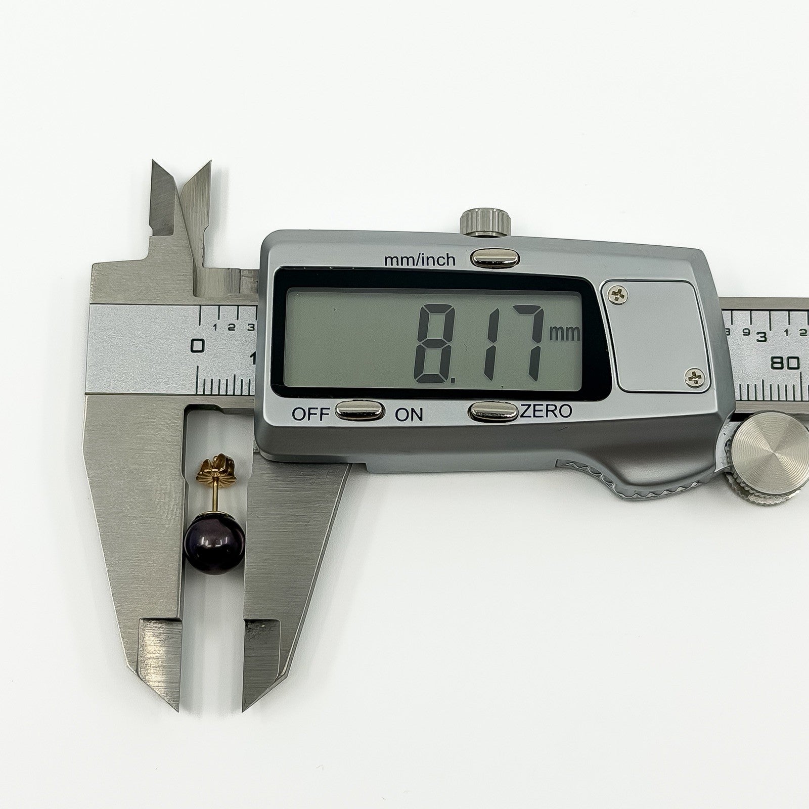 Caliper measurement showing cultured black pearl stud earring at approximately 8.17mm