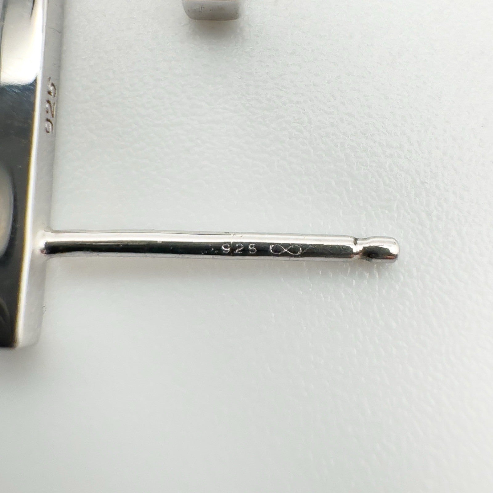 Close-up of earring post stamped 925 with infinity-style maker’s mark on sterling silver J earrings