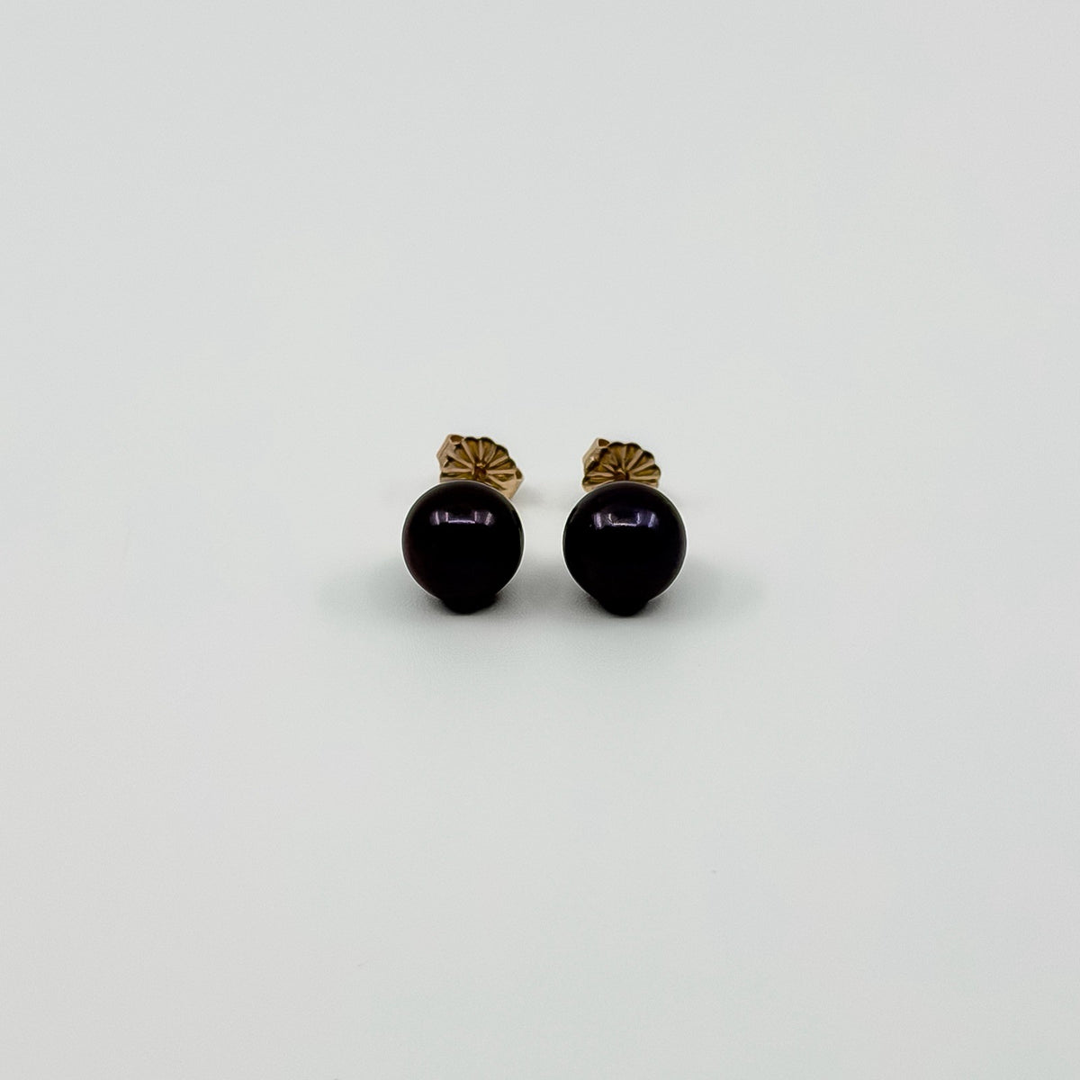 Vintage 9ct gold cultured black pearl stud earrings shown from the front with butterfly backs