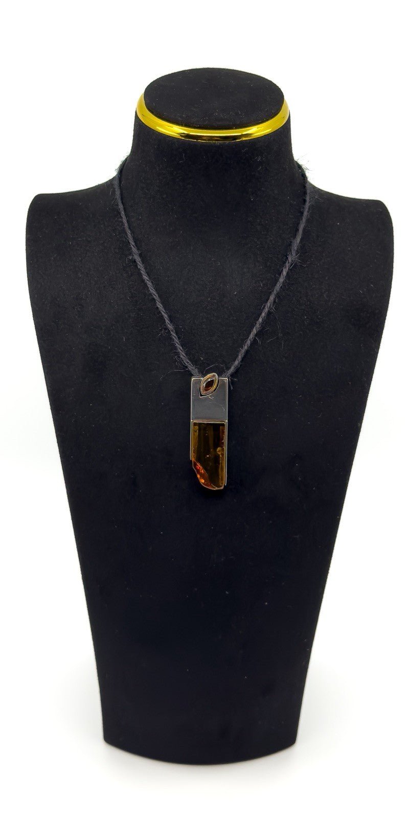 Amber and sterling silver pendant shown on a black display bust.