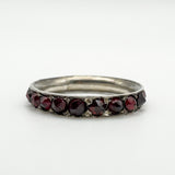 Angled close-up of garnet-set silver ring showing the row of hand-cut stones