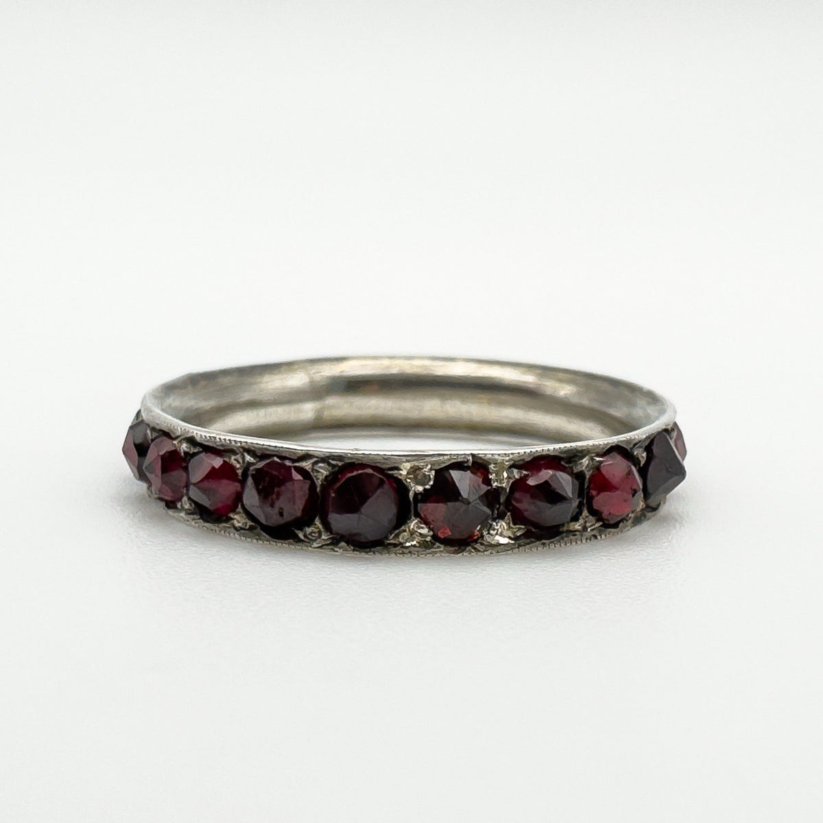 Angled close-up of garnet-set silver ring showing the row of hand-cut stones