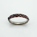 Side angle showing faceted garnets set in silver band with decorative detail