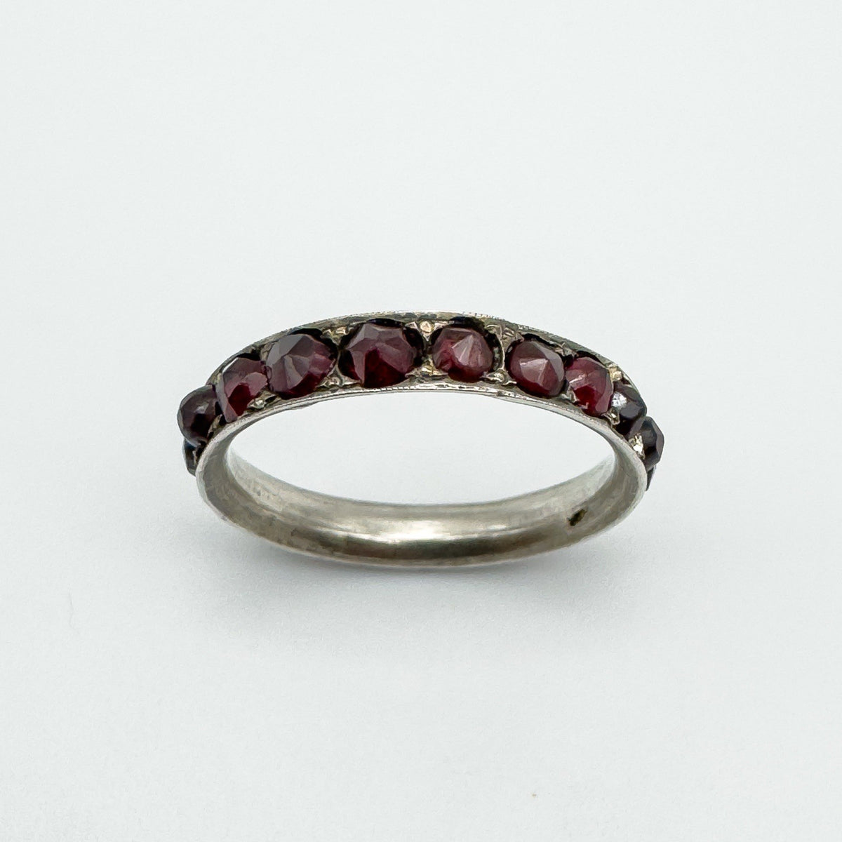 Side angle showing faceted garnets set in silver band with decorative detail