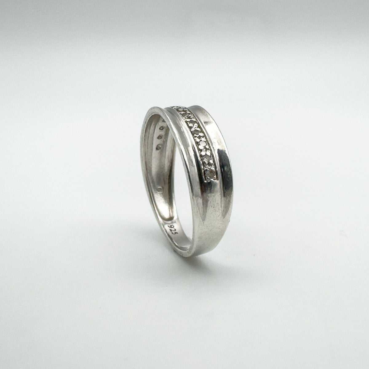 Upright angled view of sterling silver diamond band showing flush setting and 925 stamp