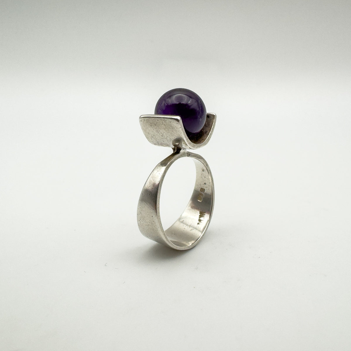 Angled view of sterling silver modernist ring with round amethyst ball