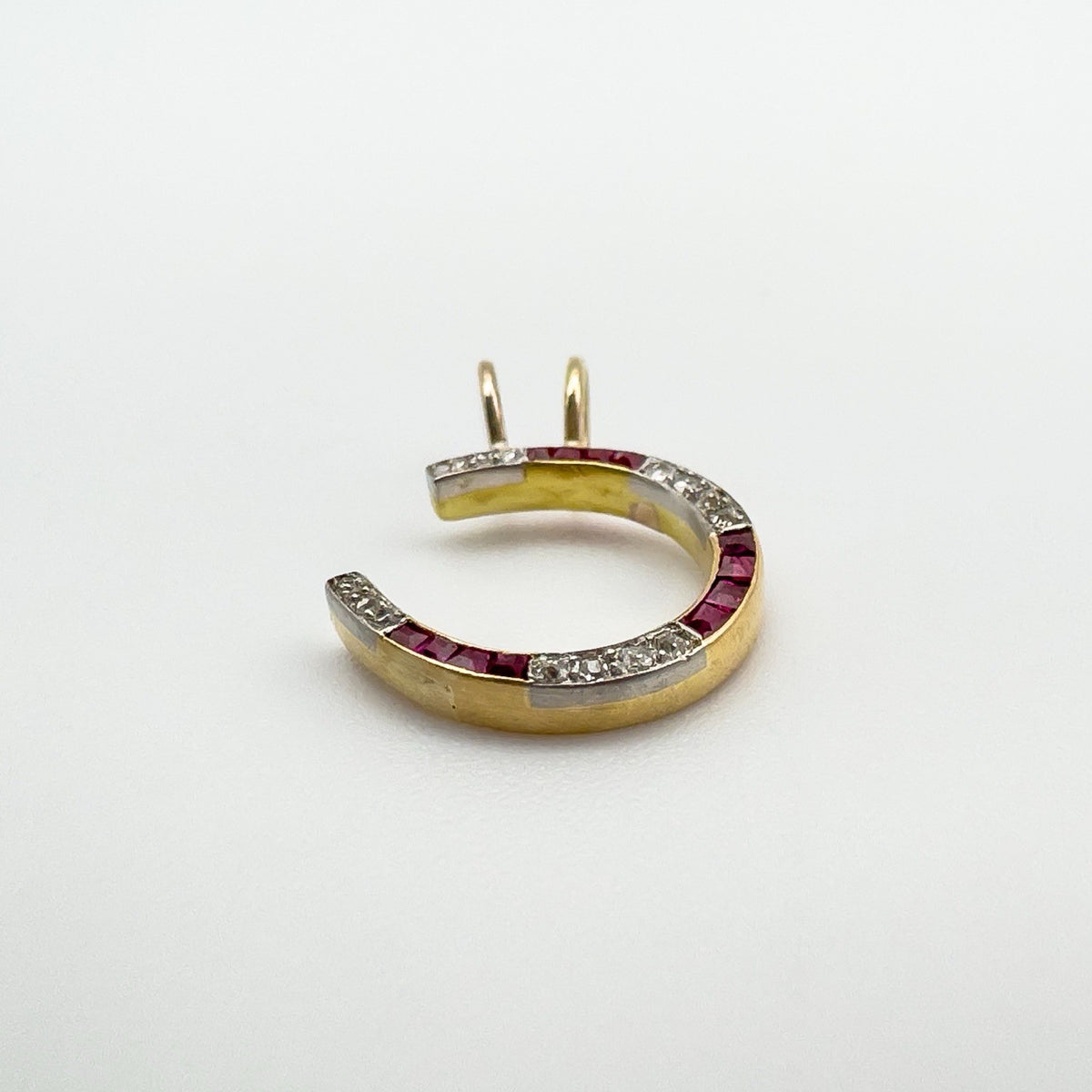 Angled view of 9ct gold horseshoe pendant with rubies and tested diamonds