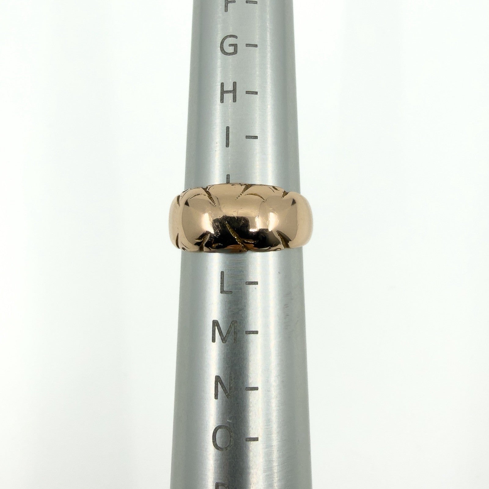 Antique 12ct rose gold band ring shown on a ring mandrel for sizing reference