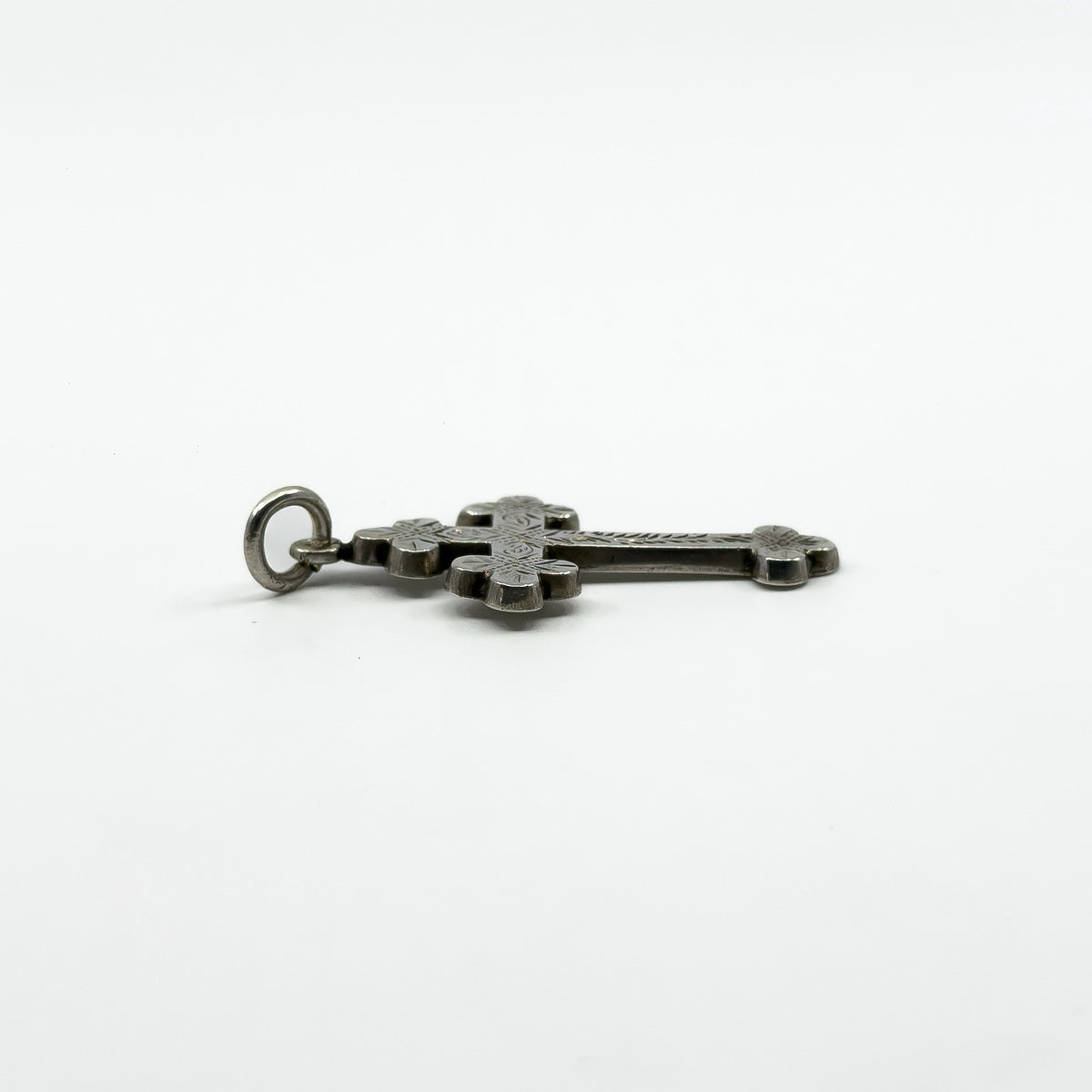 Side view of antique sterling silver engraved cross pendant showing its raised shape and bail