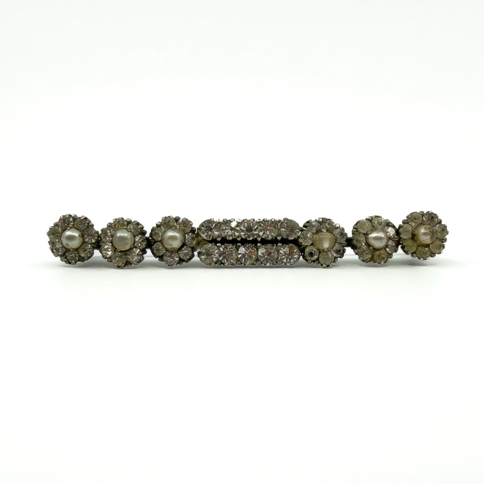 Front view of antique sterling silver bar brooch with clear paste stones and pearl clusters.