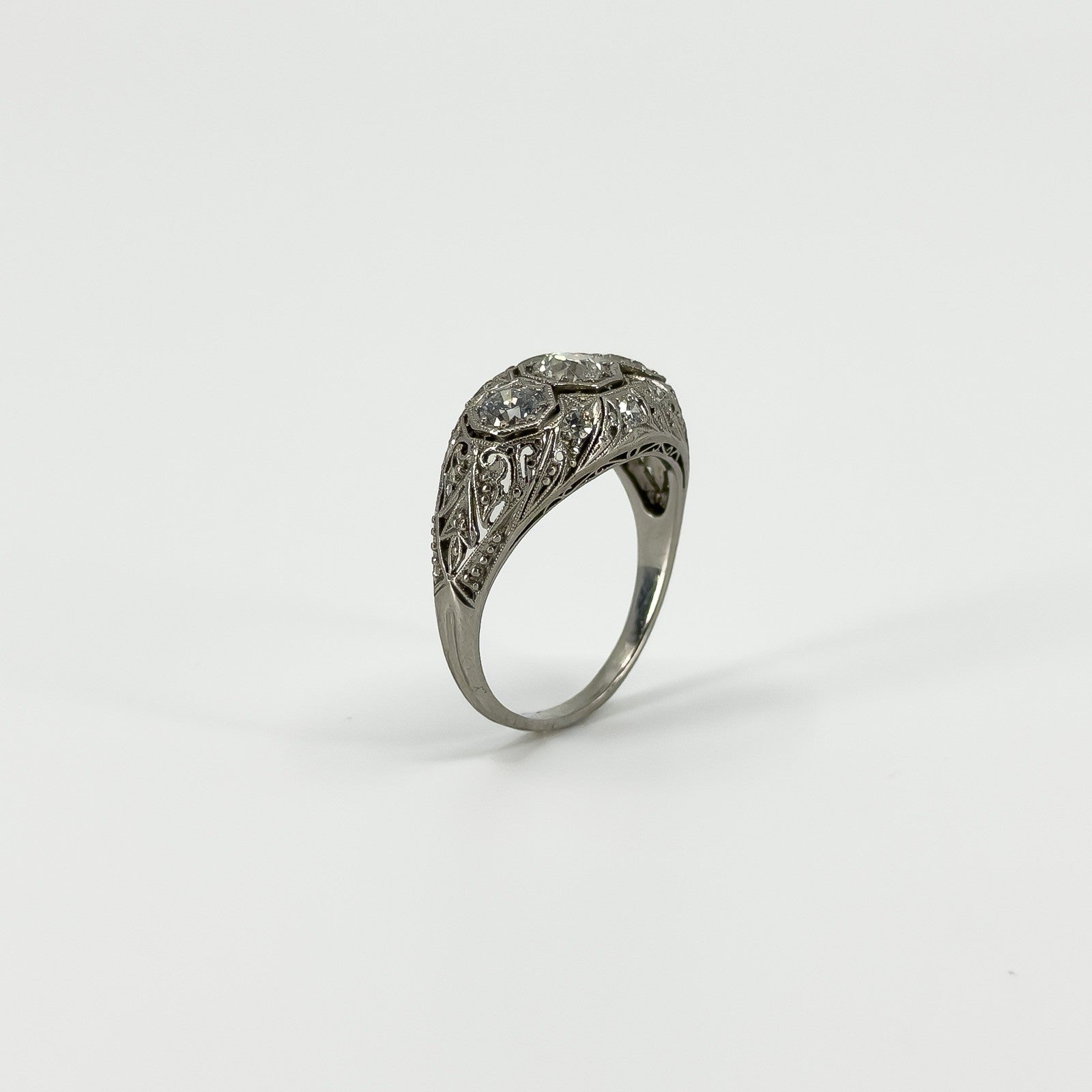Angled view of Art Deco platinum diamond ring with engraved filigree shoulders