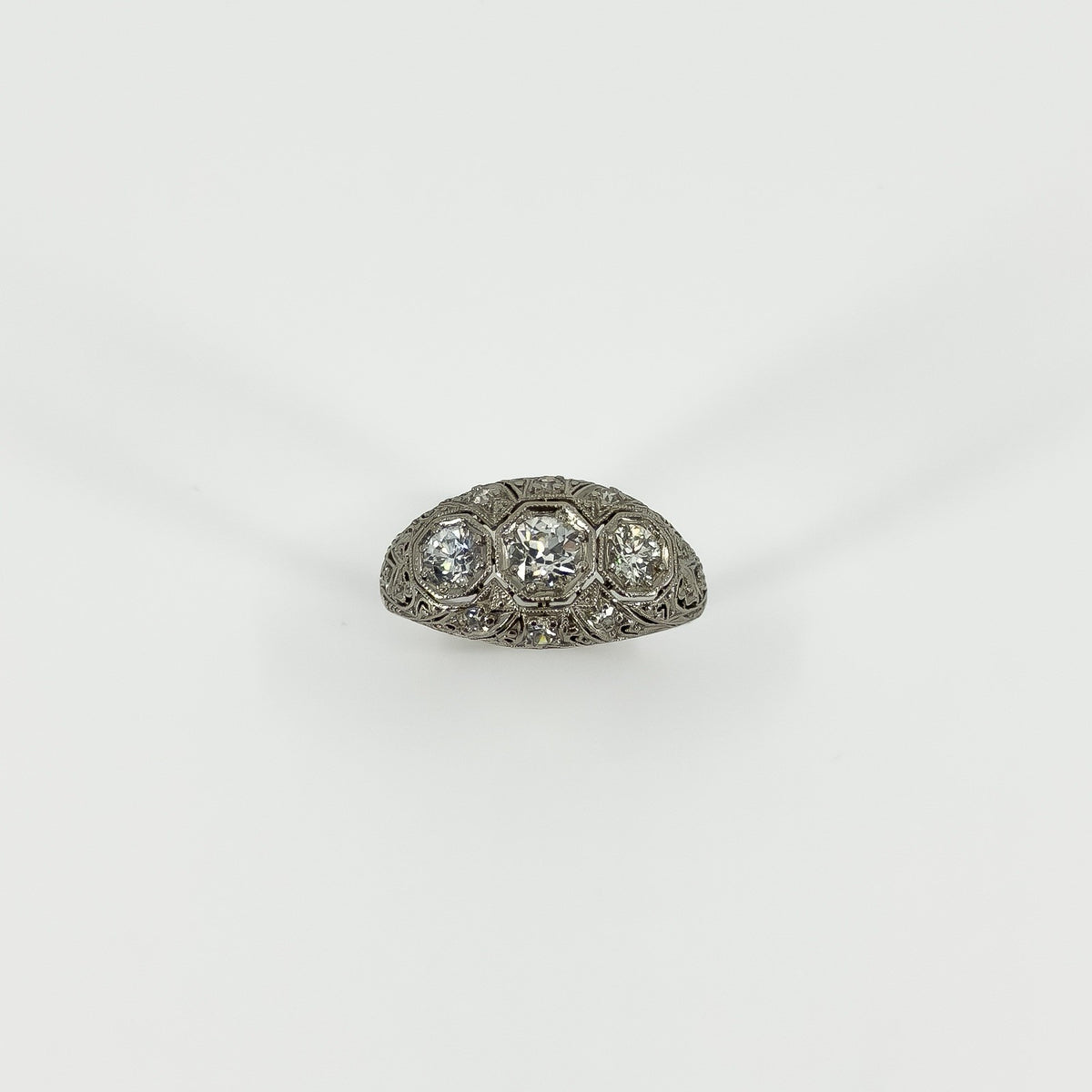 Front view of platinum diamond trilogy ring with three main diamonds and milgrain detail
