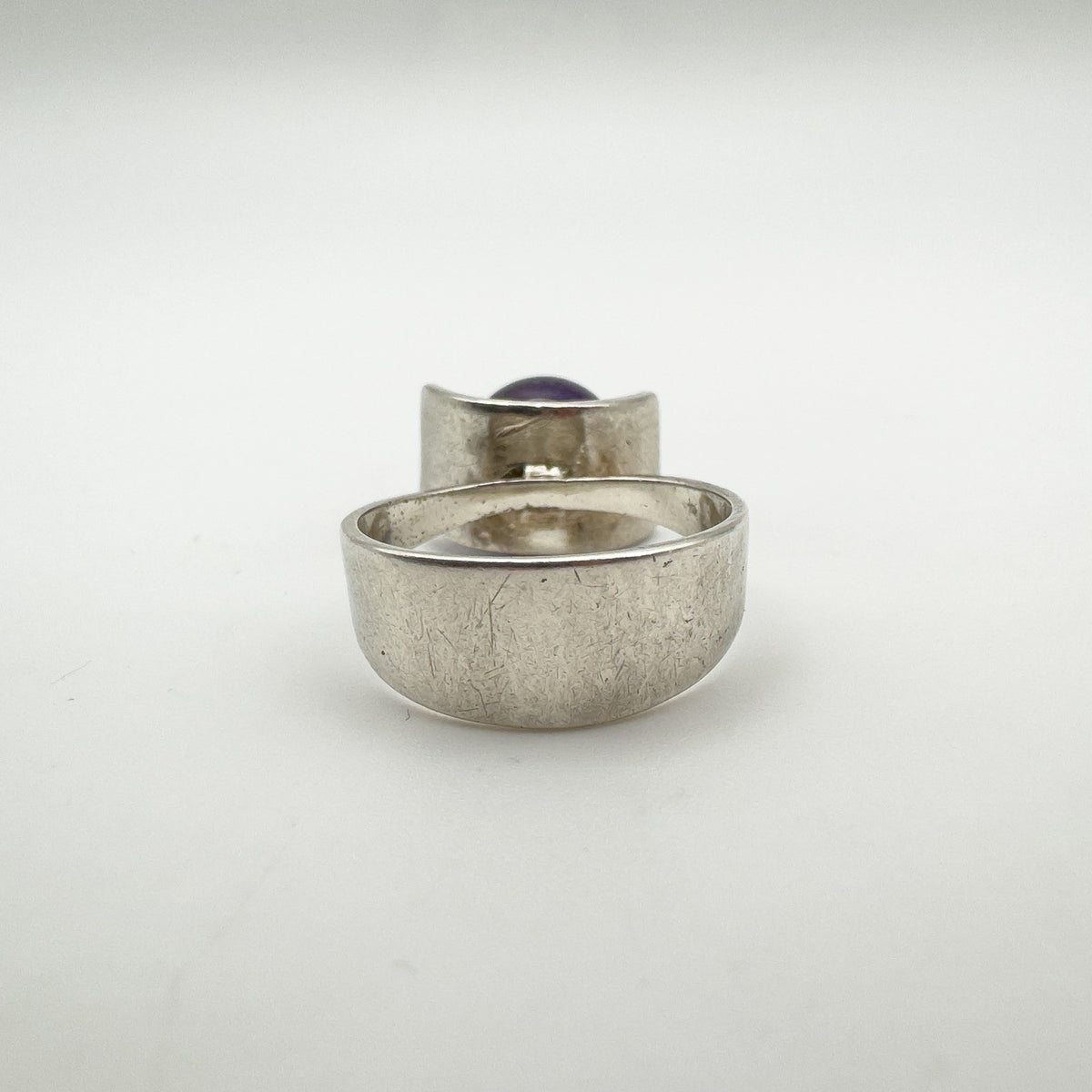 Back view of modernist ring showing thick silver band and amethyst setting