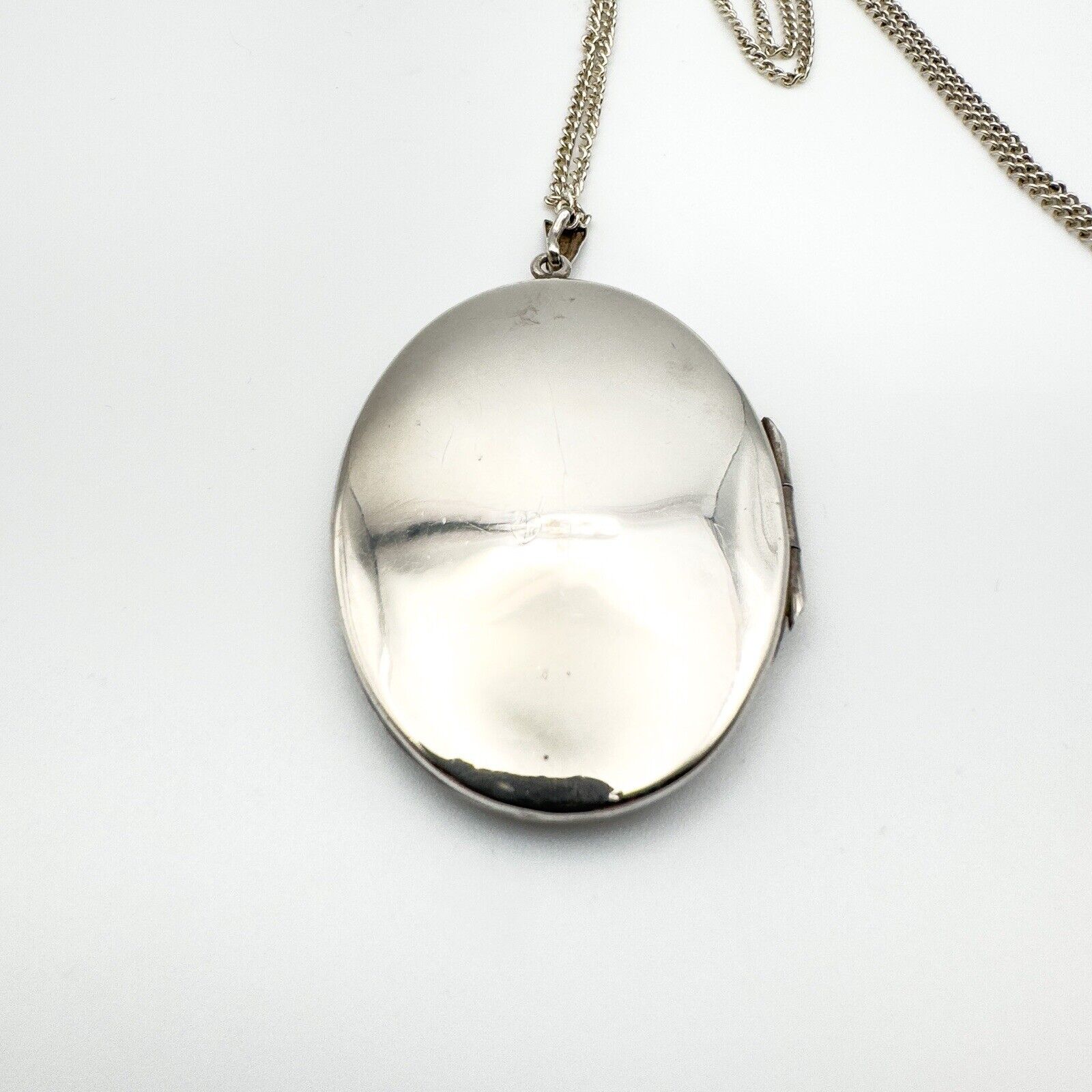 Plain back of vintage oval silver locket pendant on chain