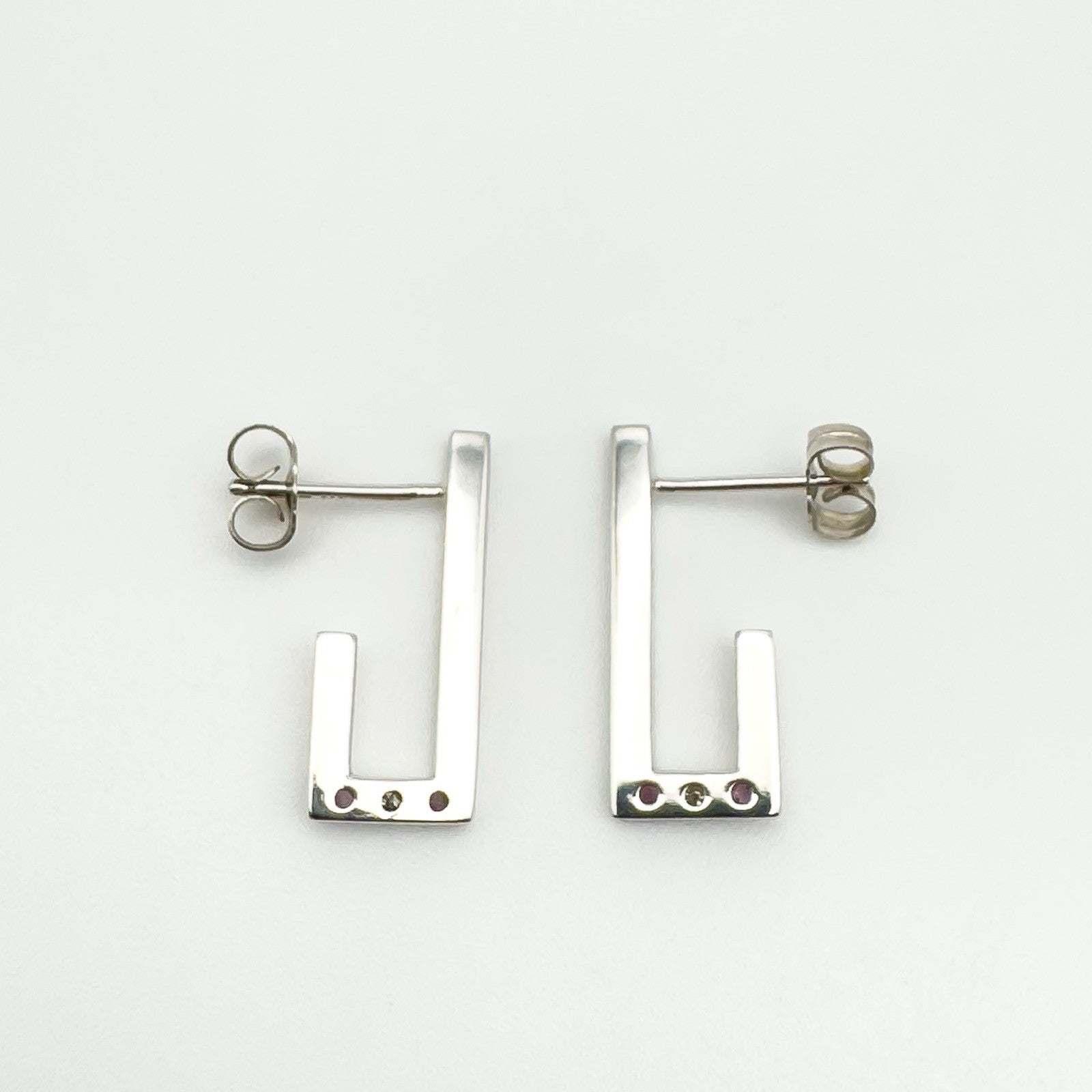 Sterling silver J earrings photographed from the back to show full polished surface and butterfly posts