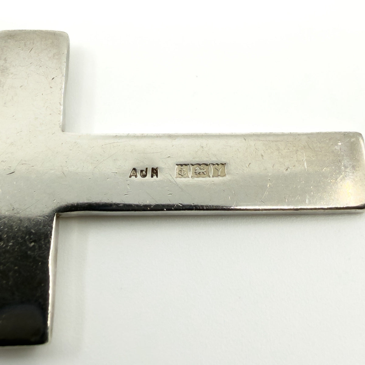 Close up of the AJH Birmingham 1973 sterling silver hallmarks on the cross pendant.