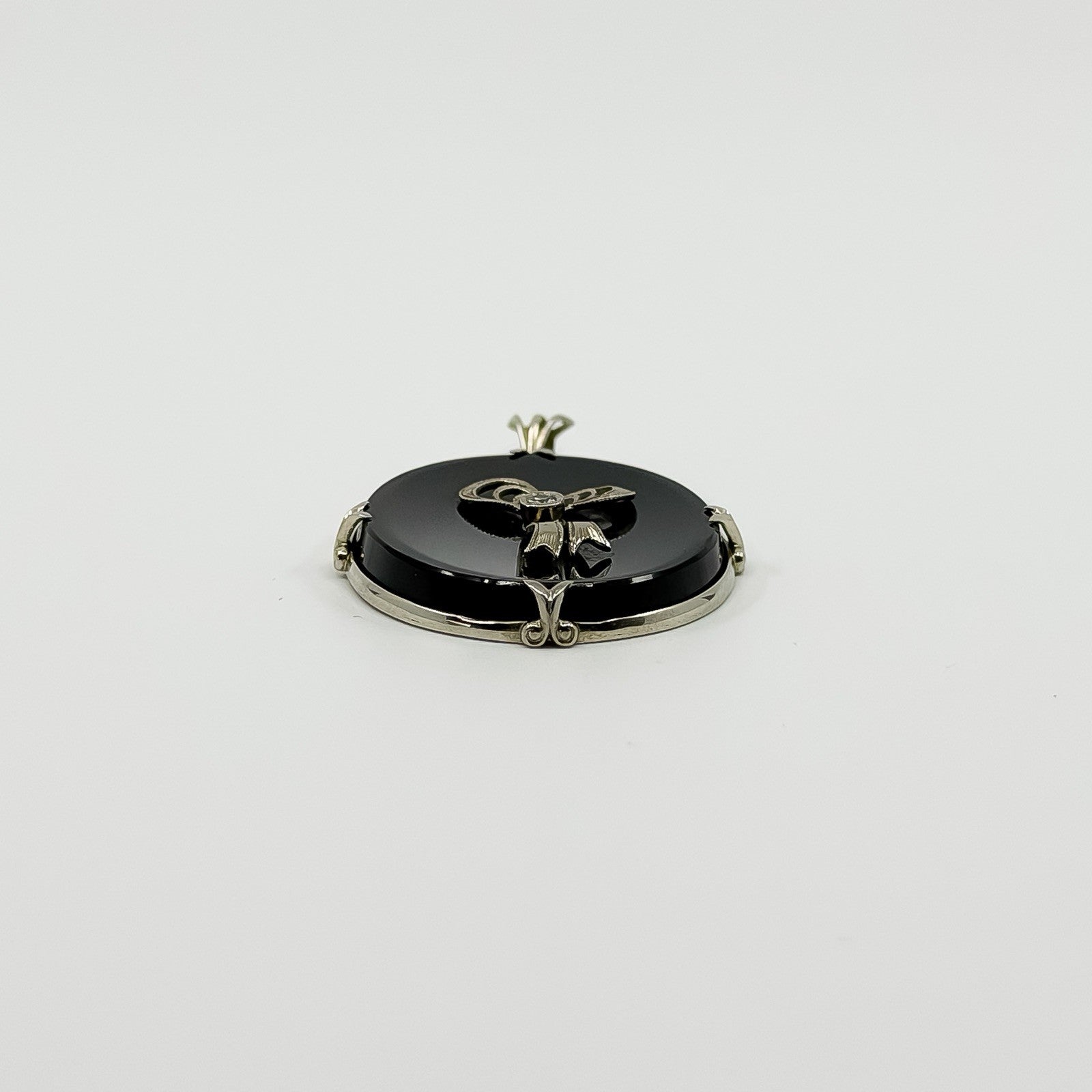 Low back view of black onyx bow pendant showing the oval reverse, white gold frame and bail.