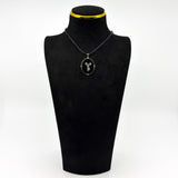 Vintage black onyx and diamond bow pendant shown on a black display bust.