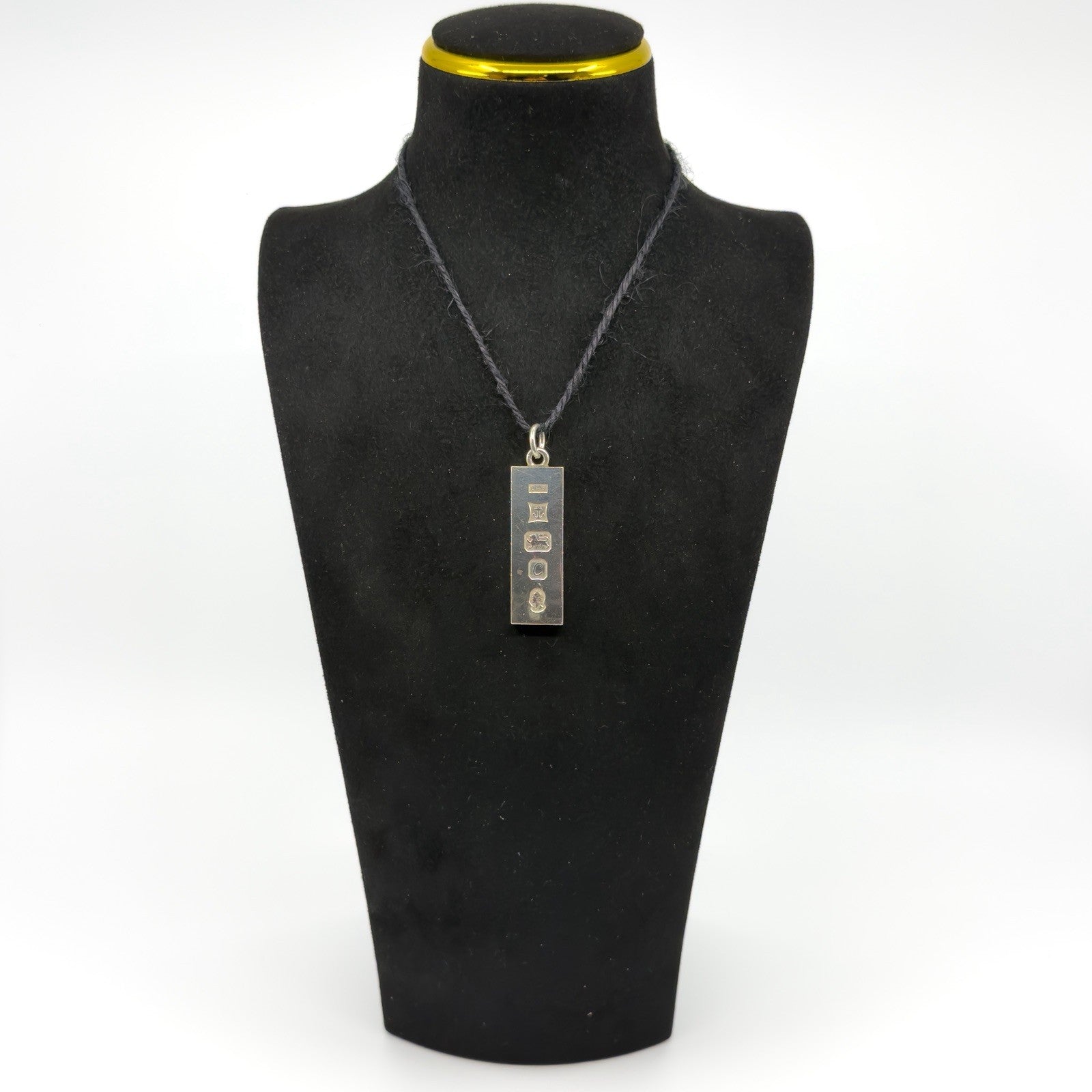 Vintage sterling silver ingot pendant shown on a black display bust