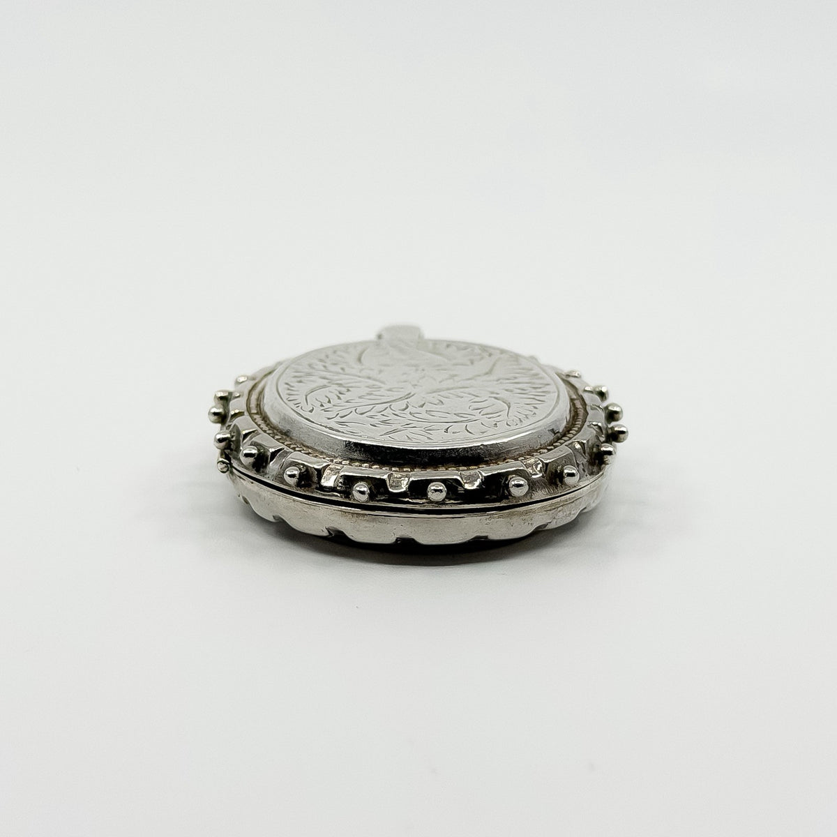 Low side view of the chunky sterling silver oval locket showing the beaded border detail