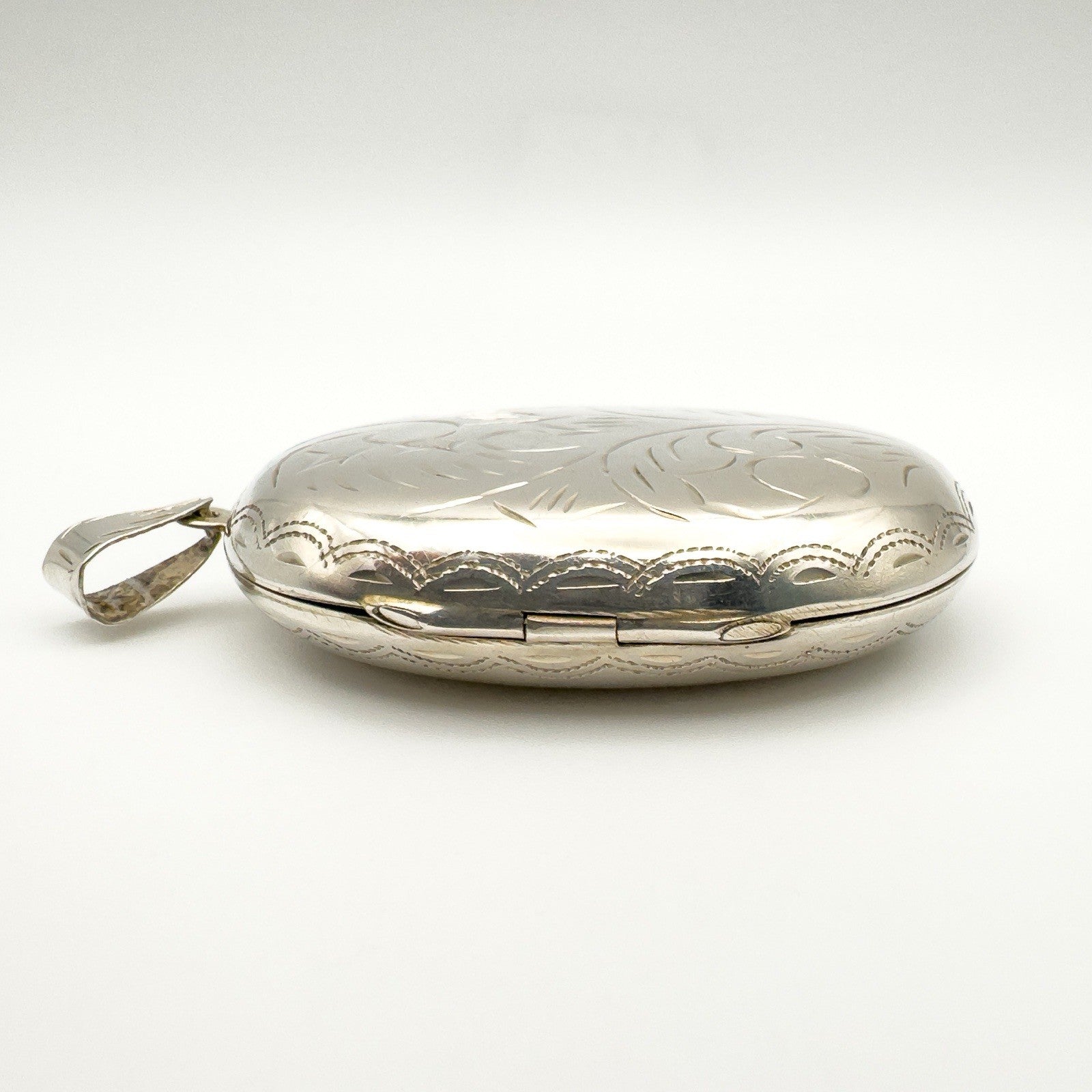 Side profile of large silver locket with secure hinge