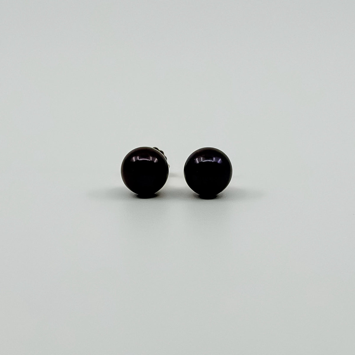 Close up of dark cultured black pearl stud earrings showing the rounded 8mm pearl fronts