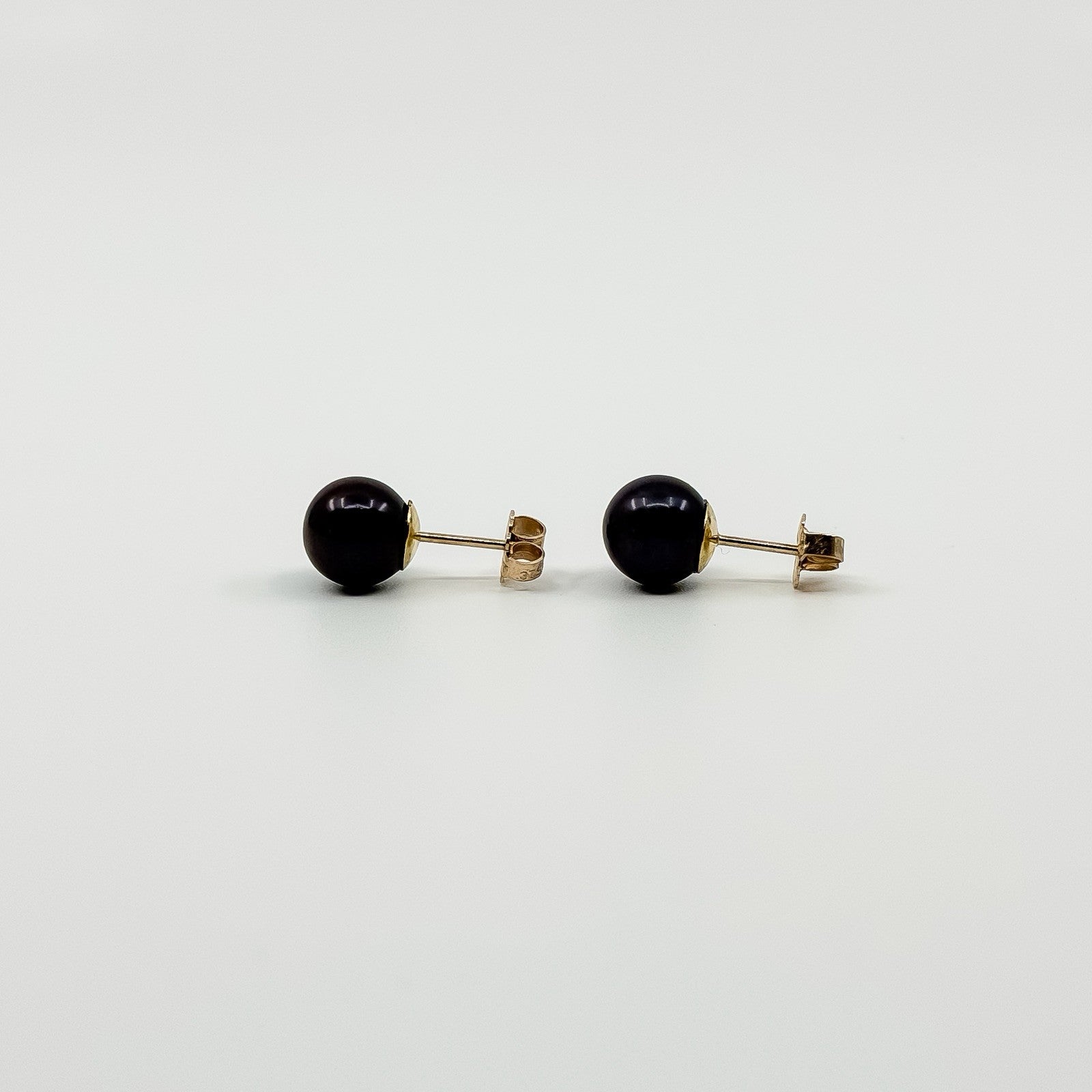 Side profile of vintage 9ct gold cultured black pearl stud earrings with straight posts and backs