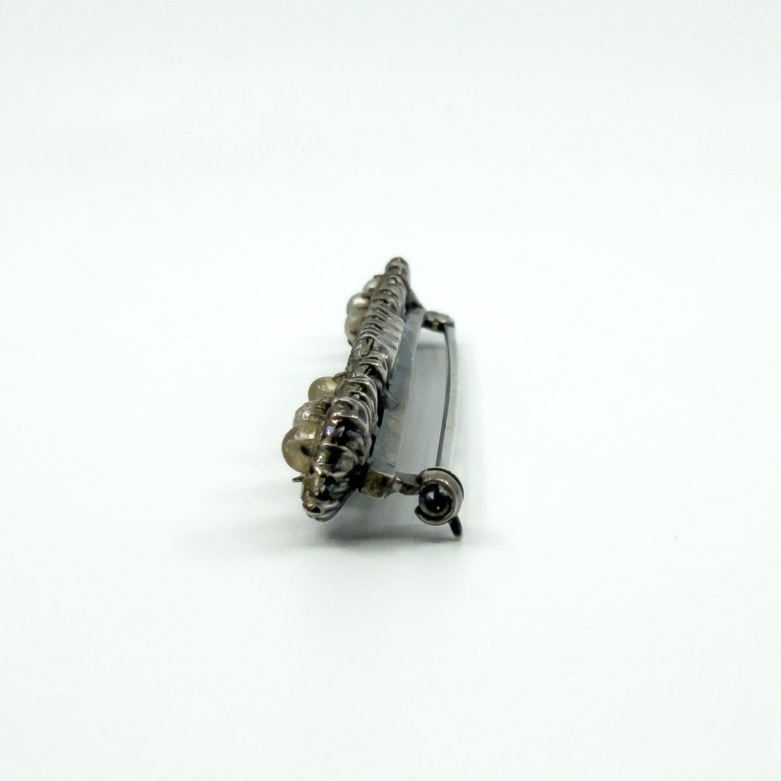 Close side view of pearl cluster end on the sterling silver bar brooch with paste accents.