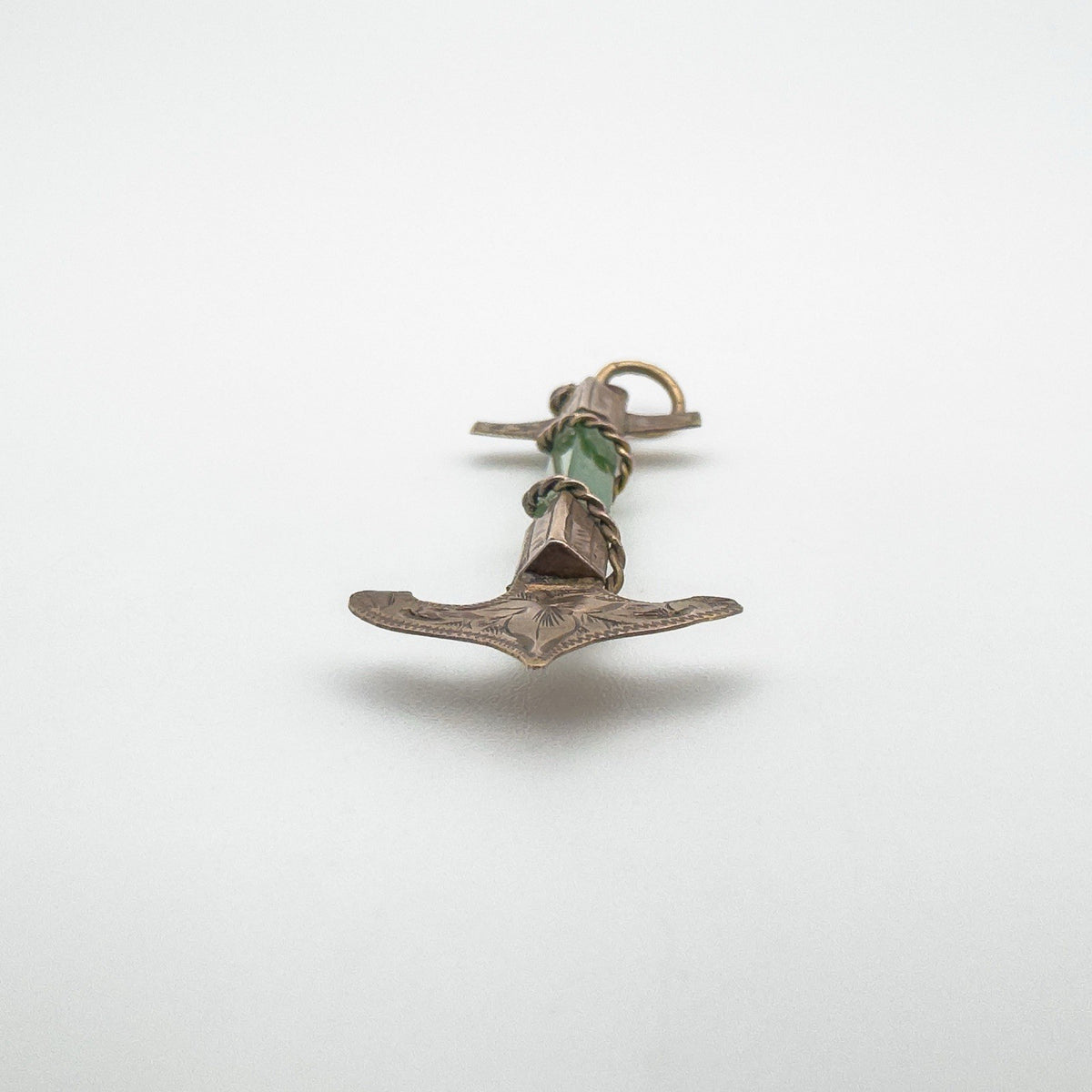 Low angle showing the engraved gold fluke and jade centre of the pendant