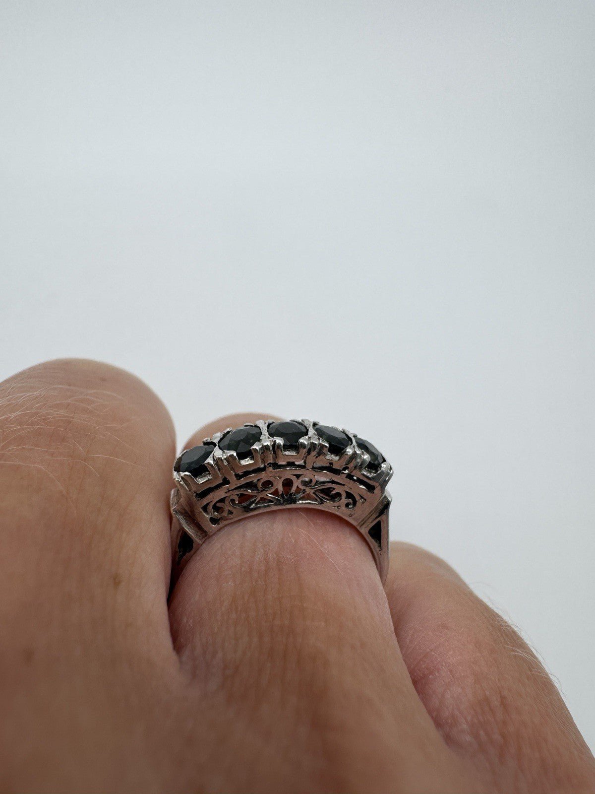 Raised sapphire setting and pierced filigree gallery shown from finger side view