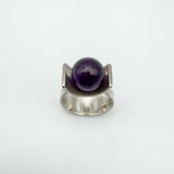 Straight front image of vintage amethyst ring with wide silver band and deep purple stone