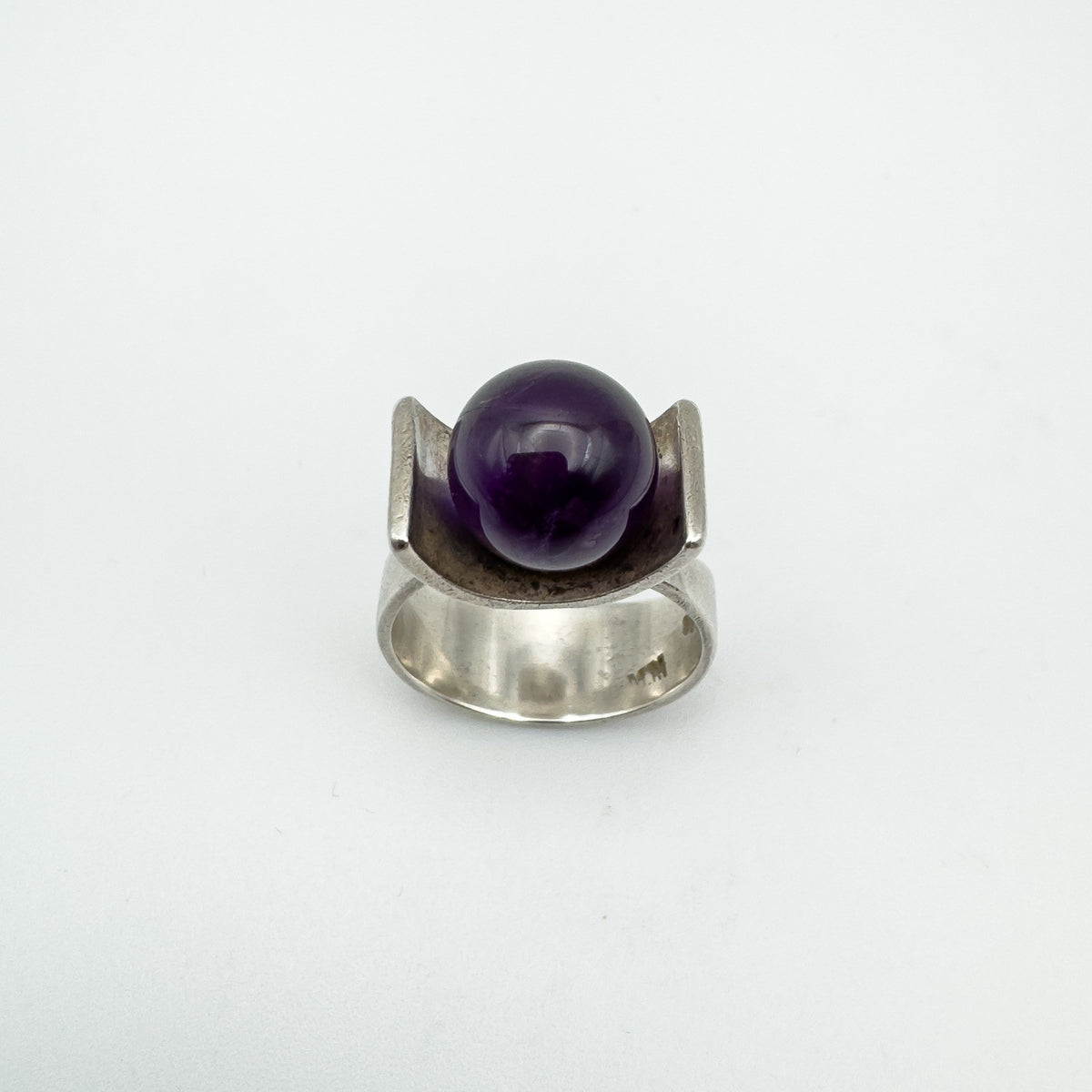 Straight front image of vintage amethyst ring with wide silver band and deep purple stone