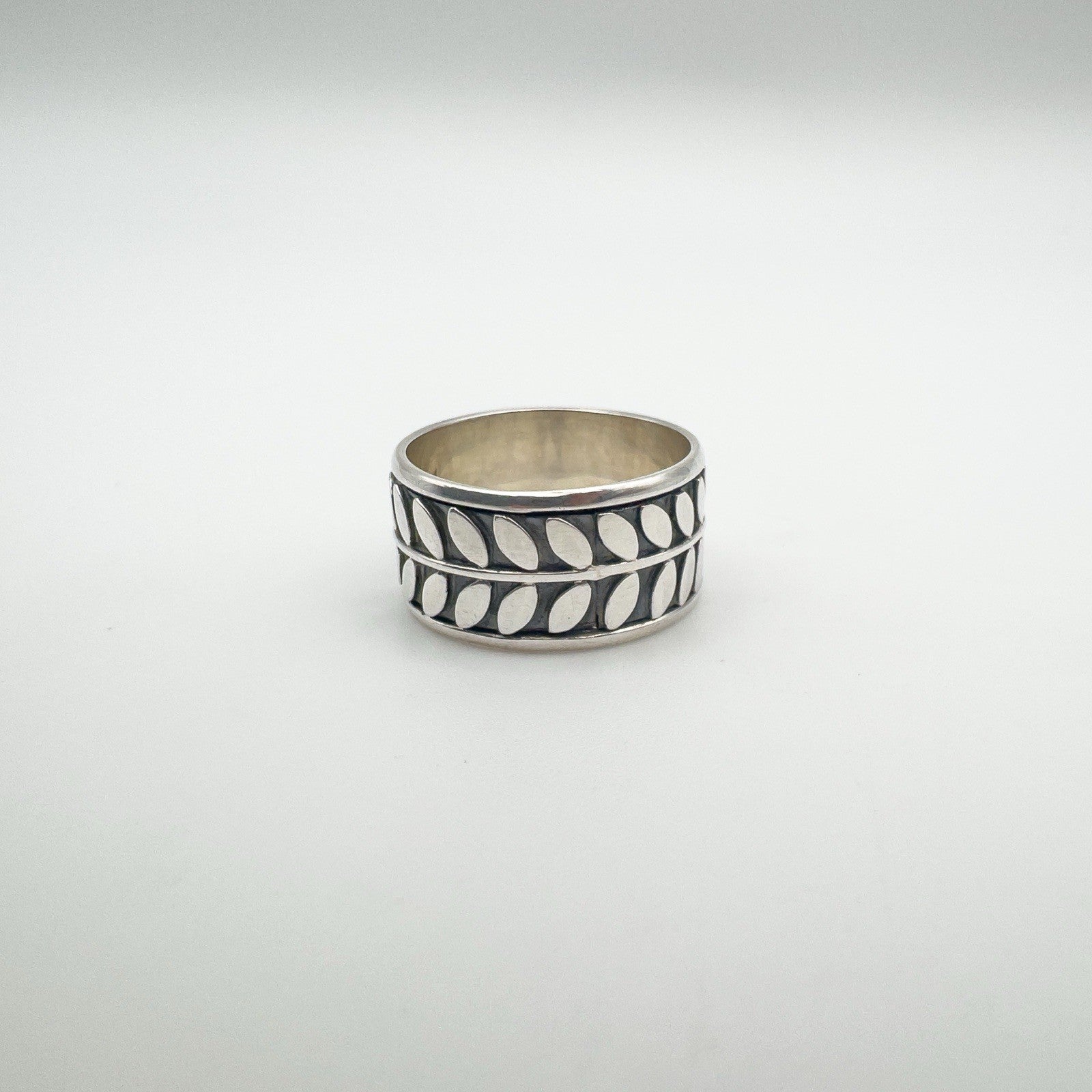 Wide sterling silver ring with engraved leaf design, front view