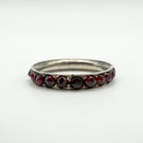 Close-up of antique silver ring set with round cut red garnets in a full eternity style