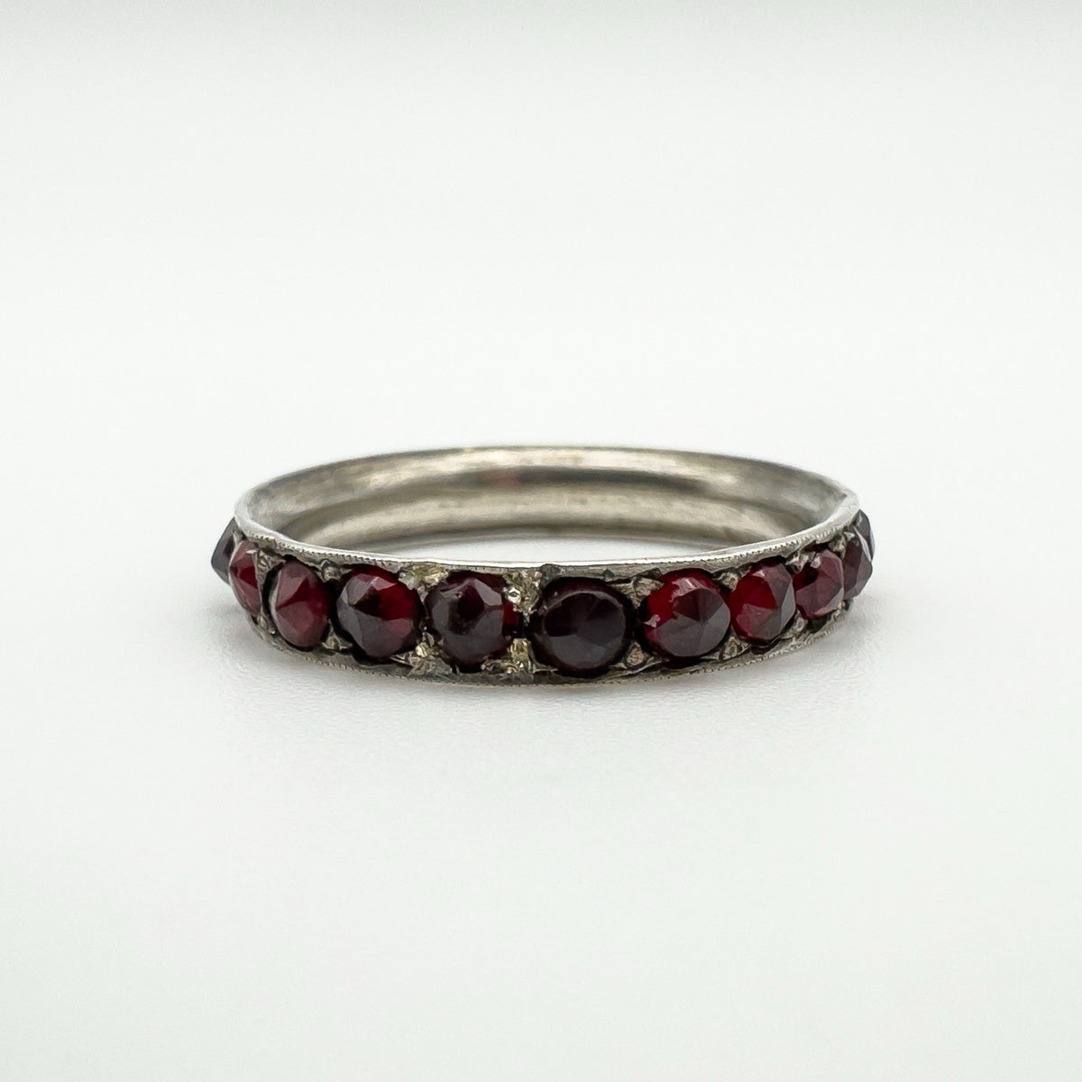 Close-up of antique silver ring set with round cut red garnets in a full eternity style