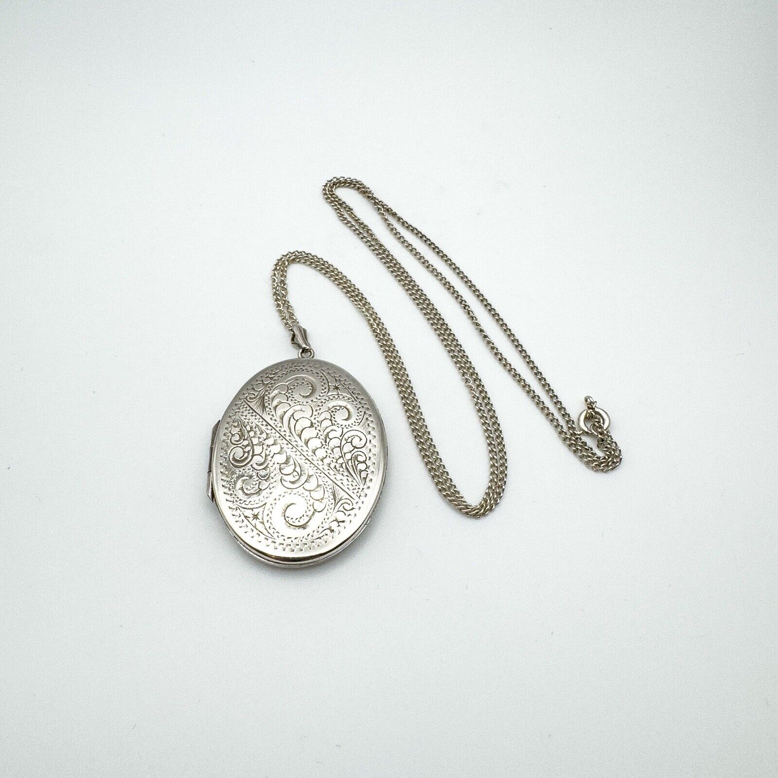 Vintage engraved oval silver locket with full 24 inch chain shown flat
