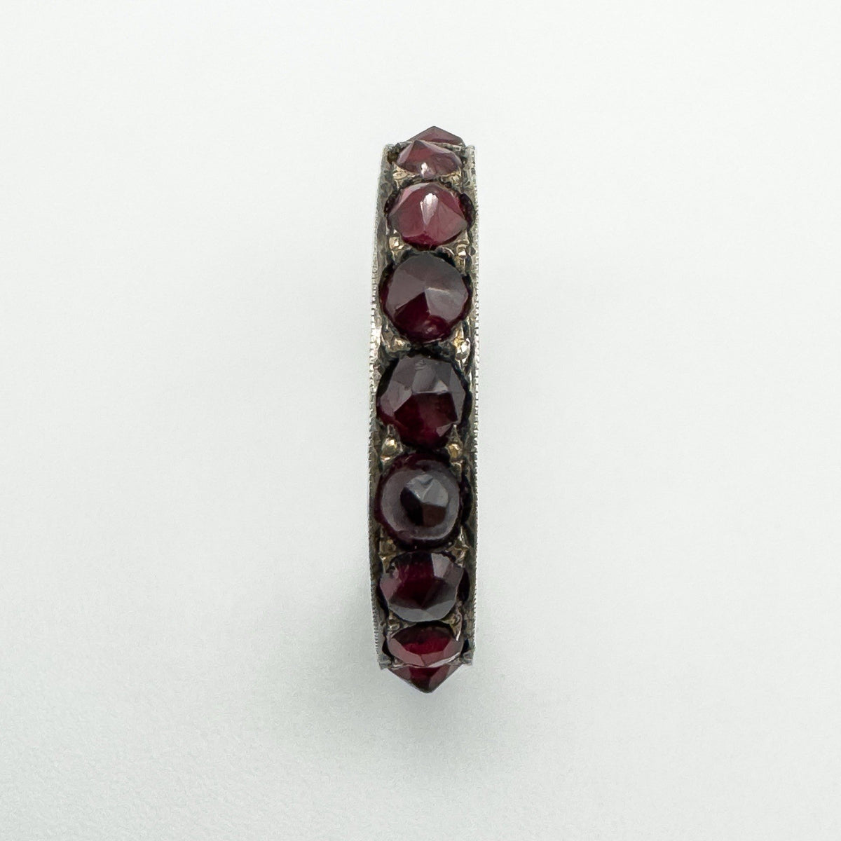 Top-down view highlighting the full row of round red garnets across the band