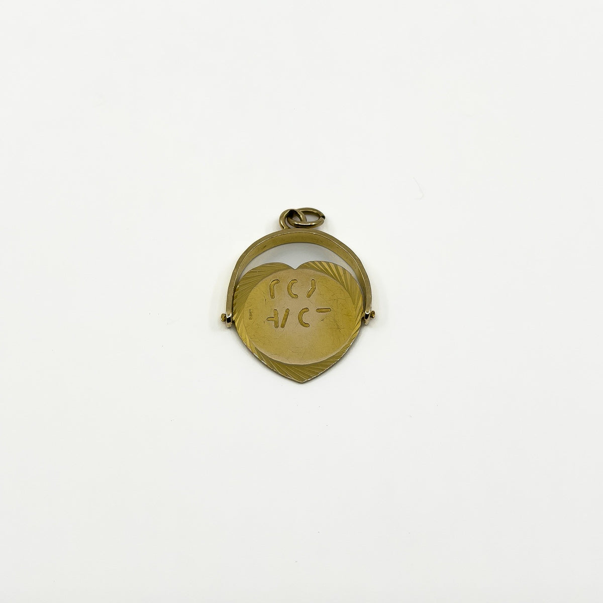 Reverse view of vintage 9ct gold heart spinning fob pendant showing engraved disc detail
