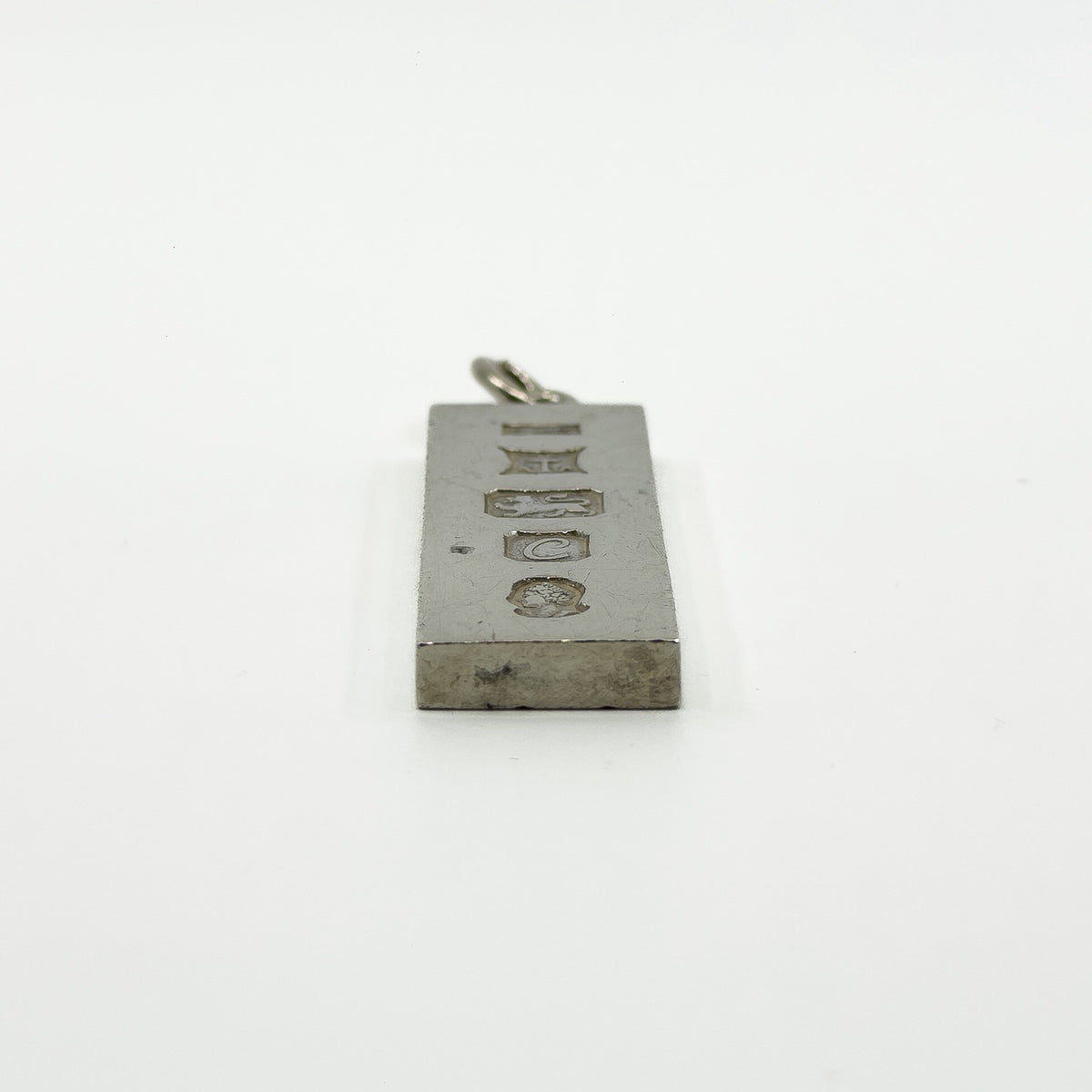 Close side view of vintage sterling silver ingot pendant with visible hallmarks and bail