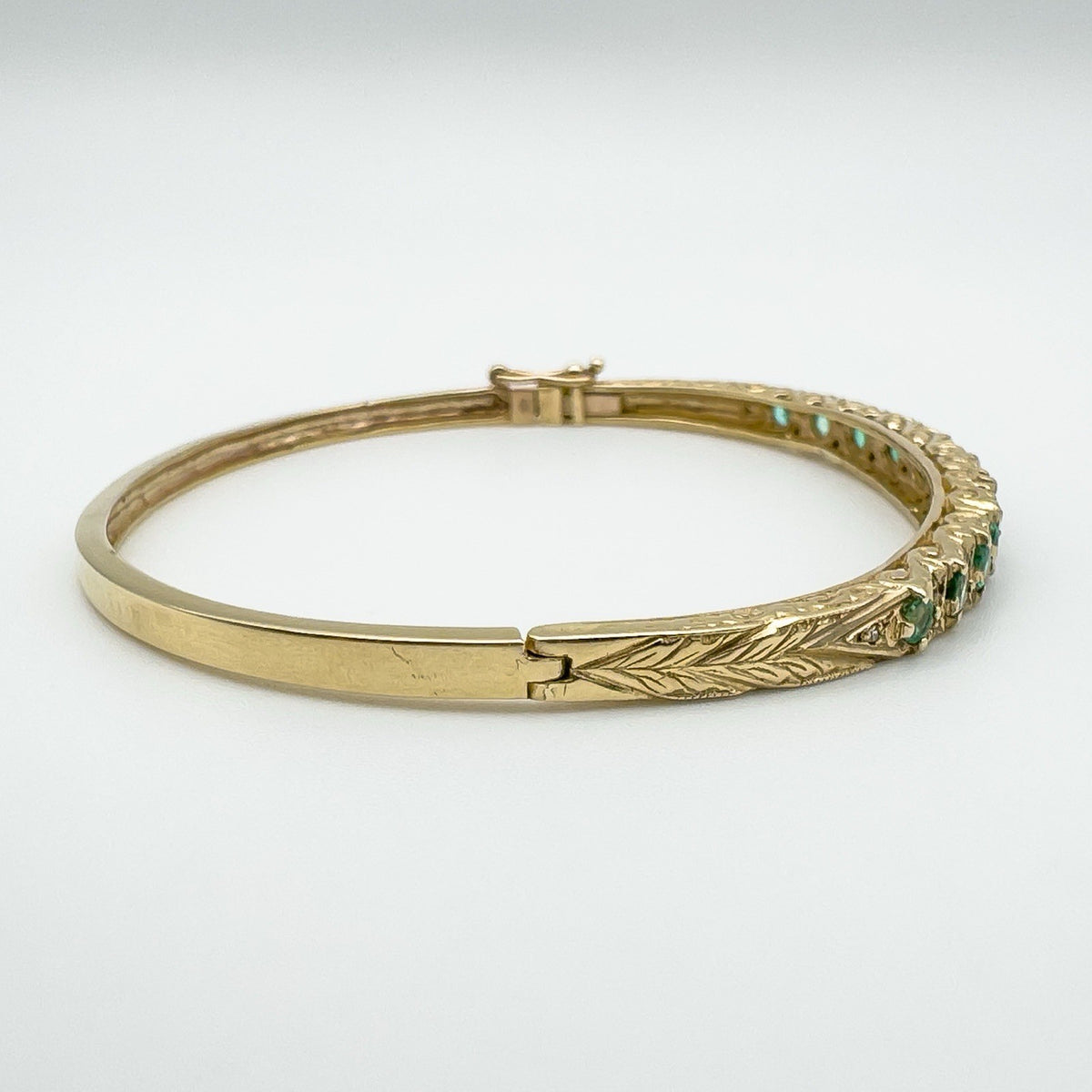 Close-up of leaf detail and push clasp on vintage gold bangle