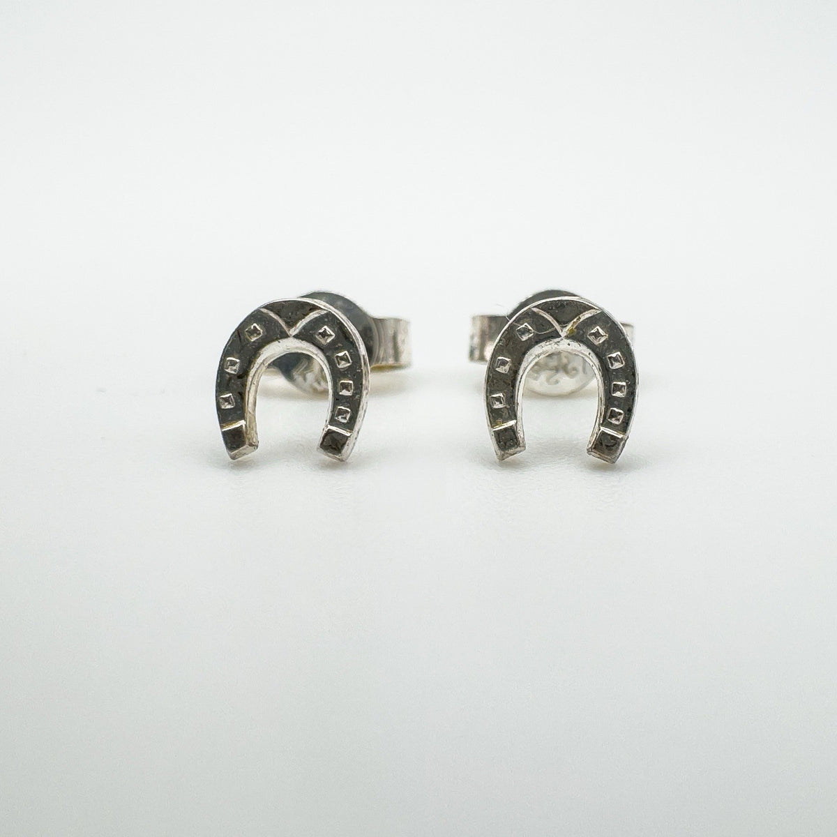 Close-up front shot of silver horseshoe earrings with square detailing