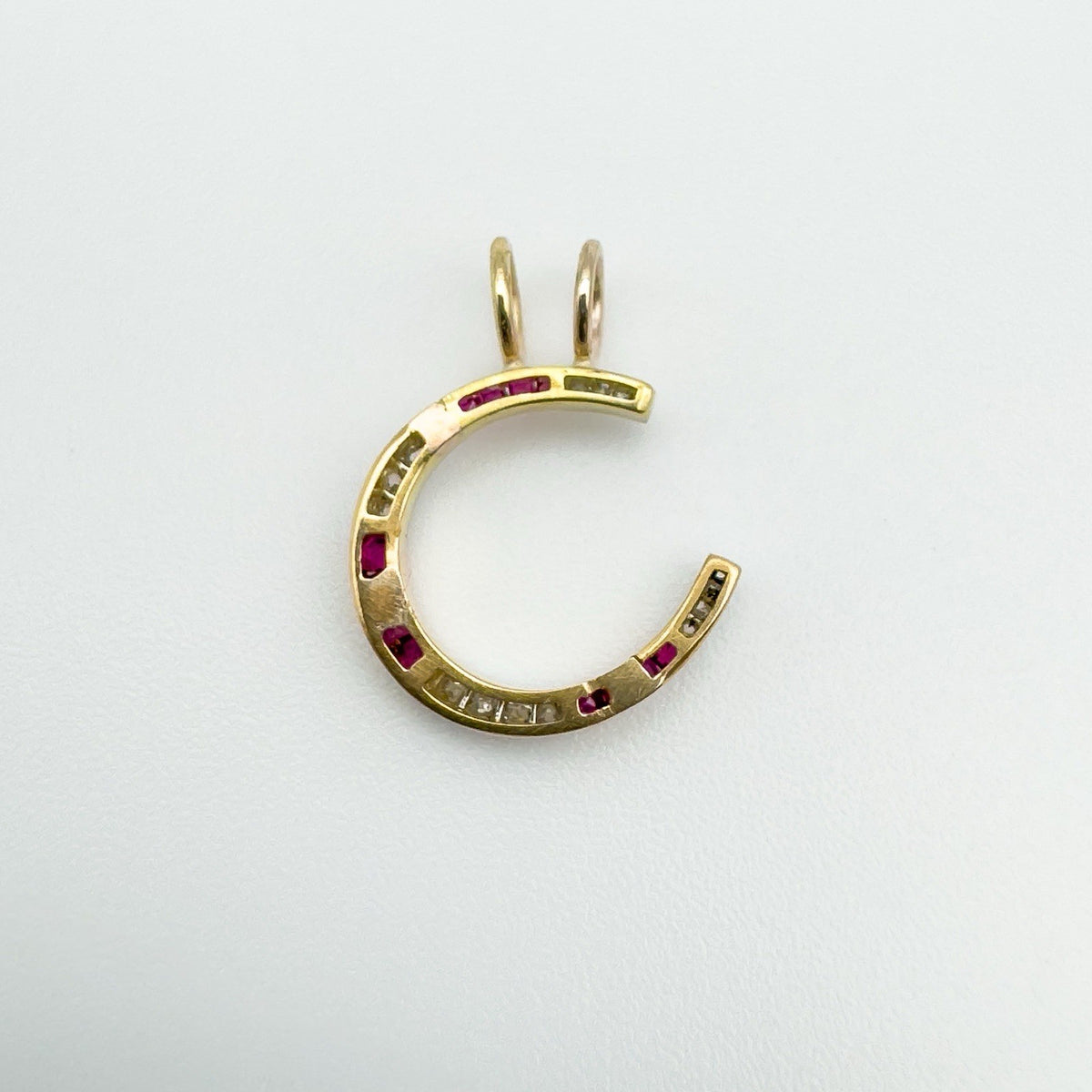 Back view of antique ruby and diamond horseshoe charm in 9ct gold