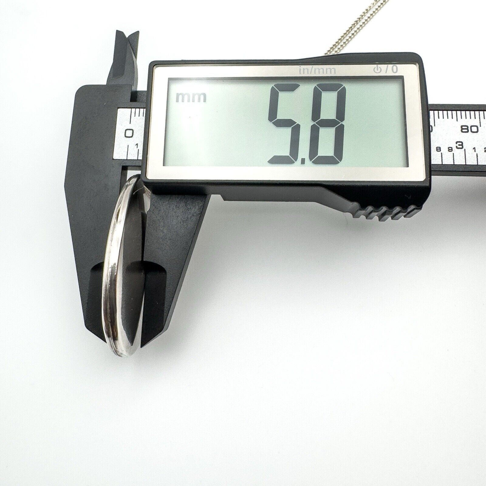 Depth of vintage silver locket measured at 5.8mm using digital calipers