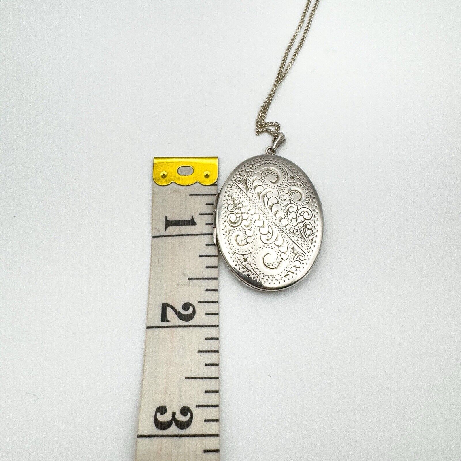 Height of engraved sterling silver locket shown next to tape measure