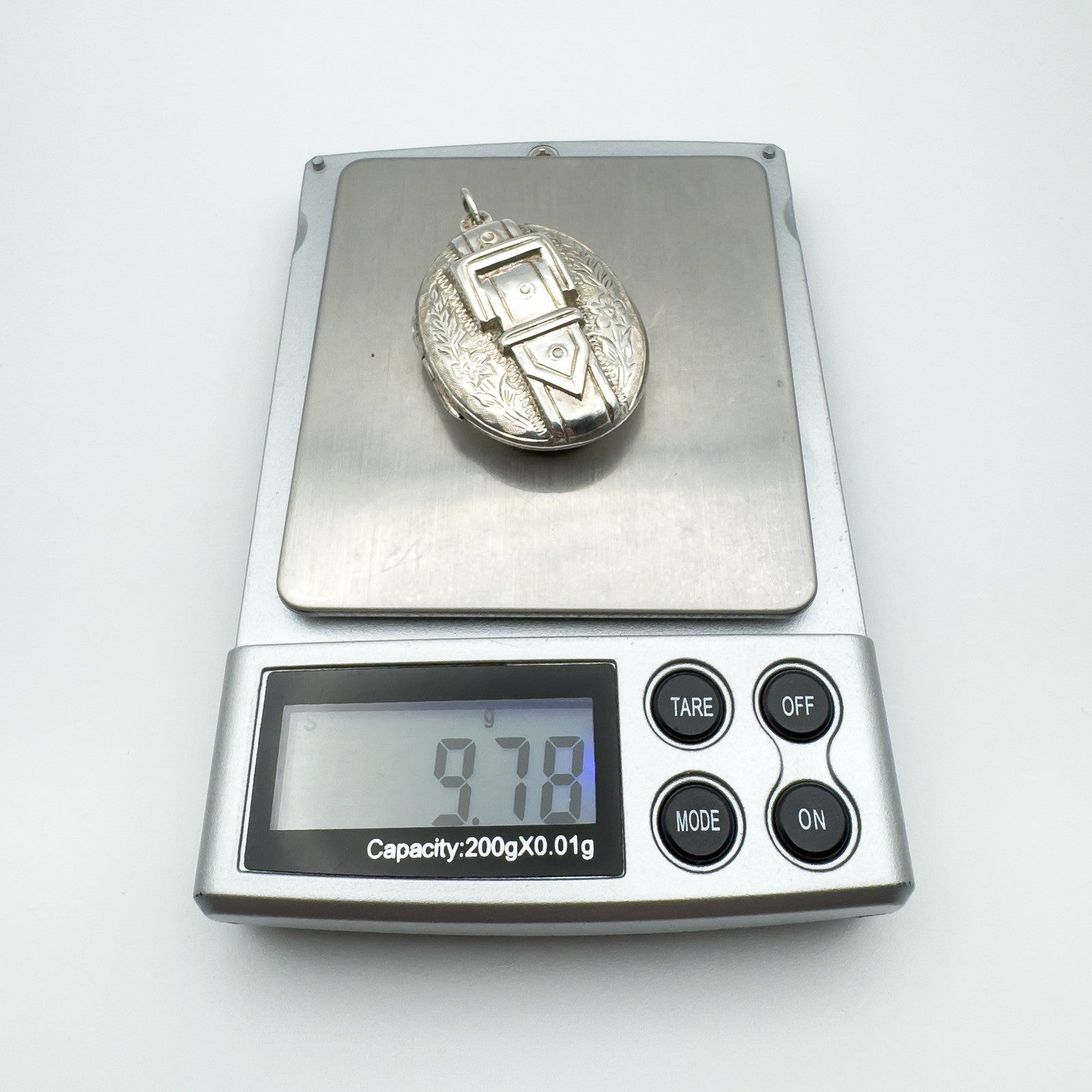Chunky vintage silver locket on digital scales weighing 9.78 grams
