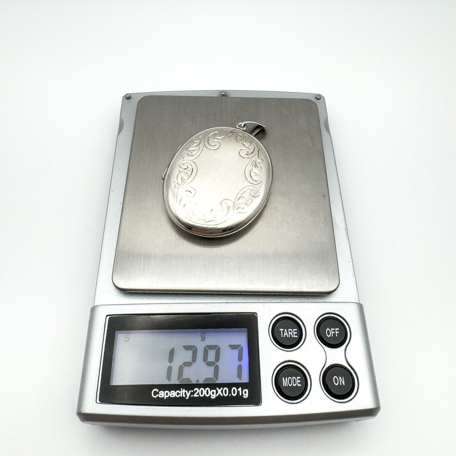 Foliate engraved sterling silver locket weighs 12.97 grams on digital scale