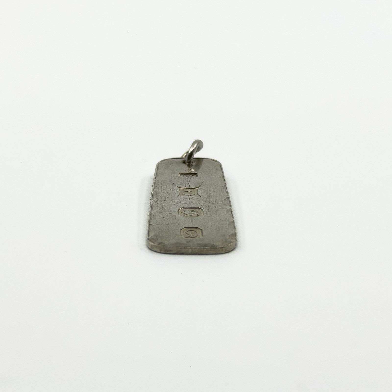 Low side view of sterling silver ingot pendant with Birmingham hallmarks and attached jump ring.