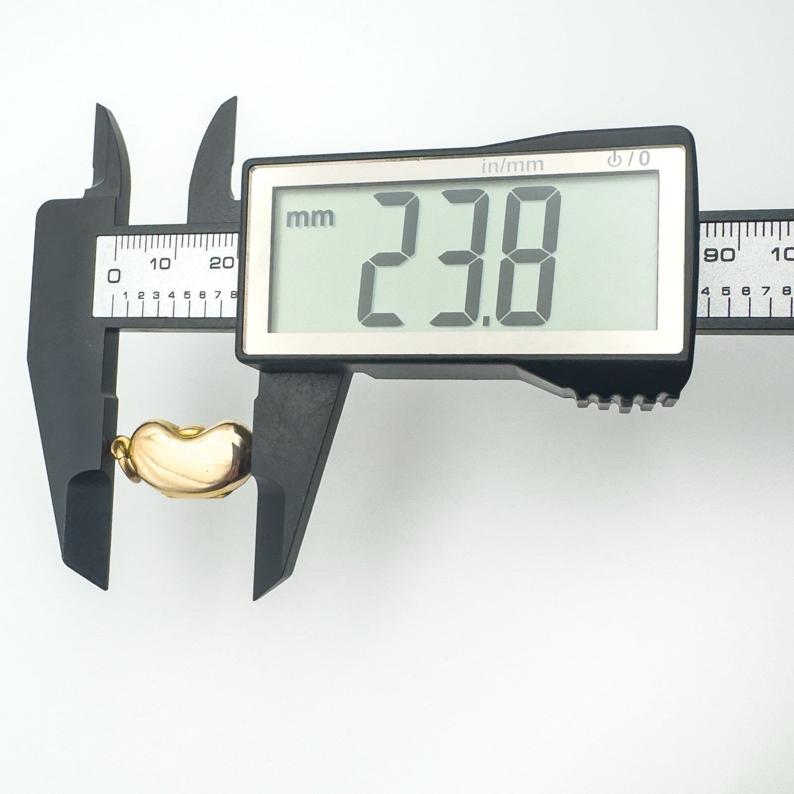 Digital caliper showing kidney bean locket measures approximately 23.8mm long